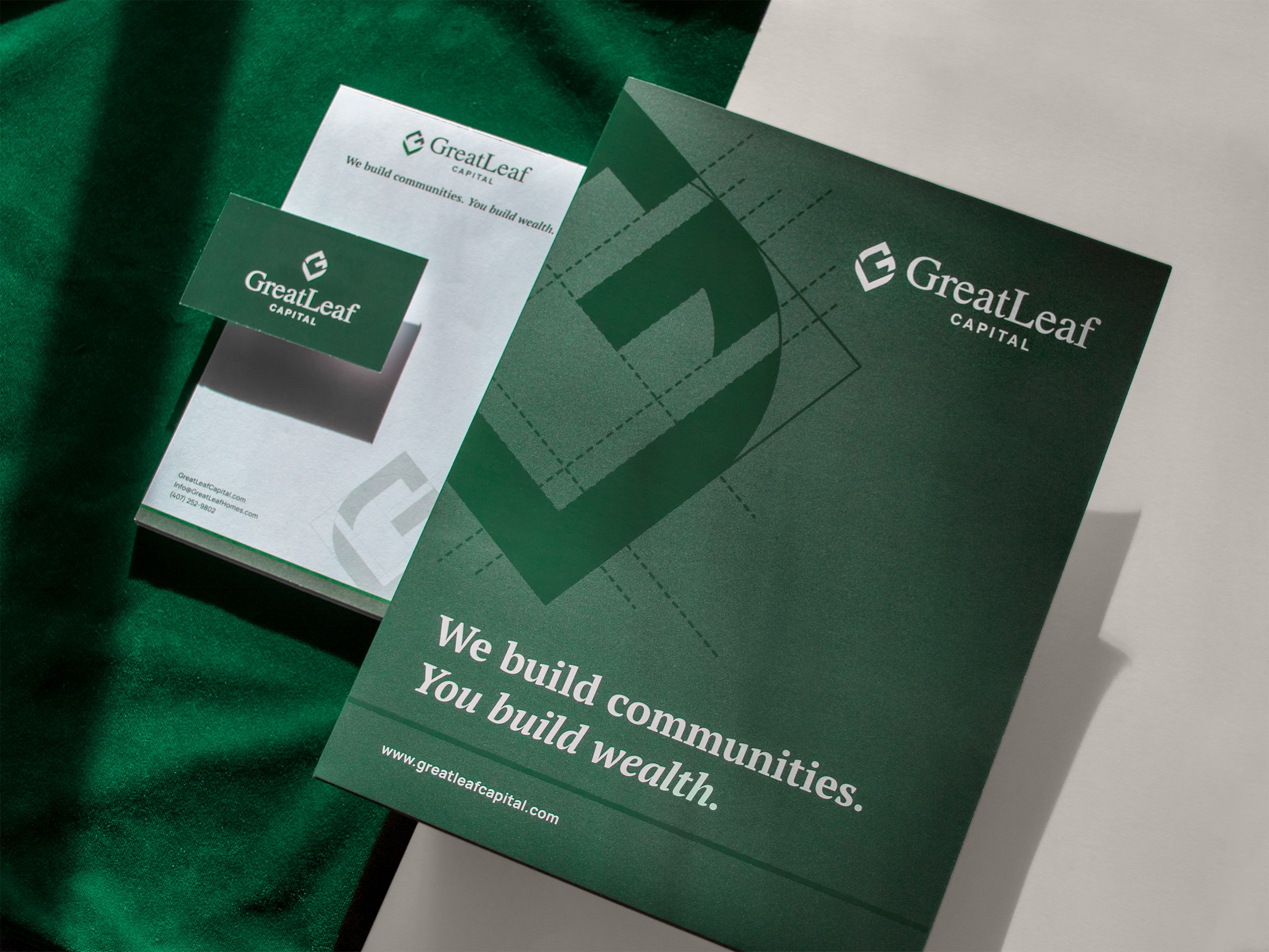 Photos of print collateral showcasing the GreatLeaf Capital branding. Materials include a branded folder, business cards and a notepad, all featuring predominantly rich green colors.